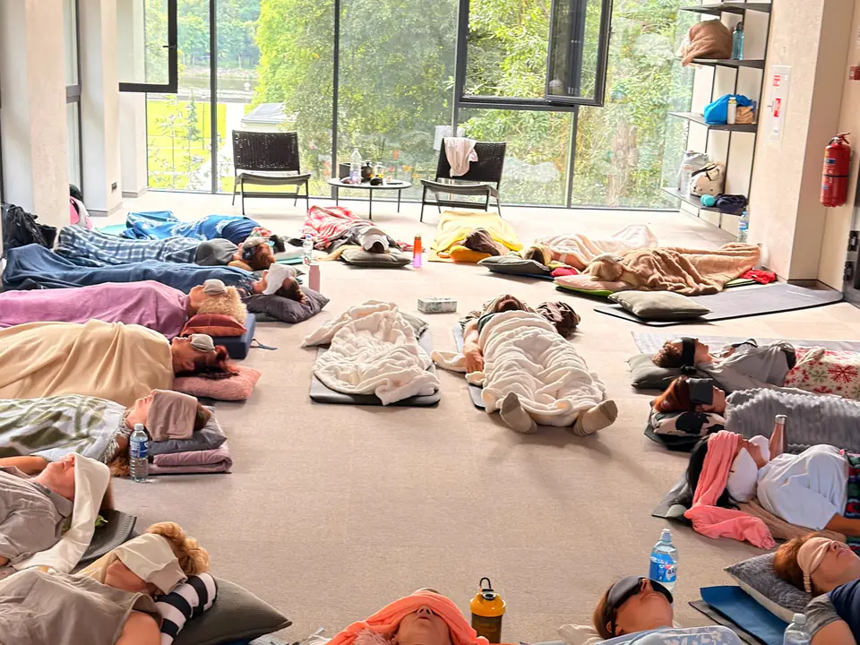 Una sala durante una sessione: persone sdraiate sotto le coperte, con gli occhi chiusi